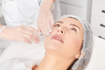 Cosmetologist makes rejuvenation injection in woman face skin, anti aging revitalization cosmetic...