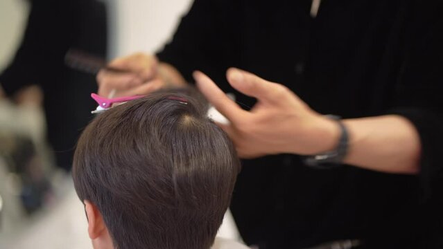 男の子の髪にヘアアイロンをかける男性美容師
