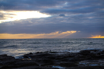 God rays shining through clouds over the ocean early in the morning. 