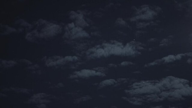 Scenic view of fluffy clouds in the dark sky at nighttime