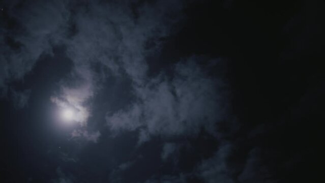 Timelapse of the clouds moving in the dark sky with the shining sun