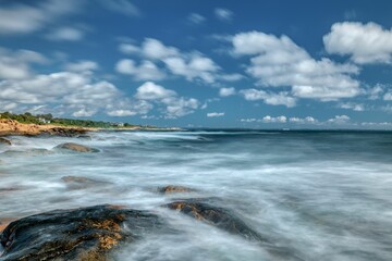 Mesmerizing view of a seascape with white waves and a rocky beach against a cloudy sky