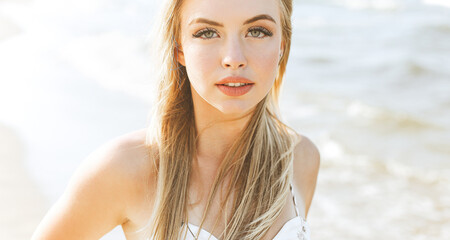 Happy blonde woman in free happiness bliss on ocean beach standing straight and posing