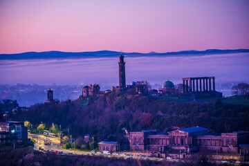 Scenic view of Arthur's Seat on Calton Hill covered with clouds at pink sunset in Scotland