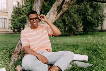 Portrait of happy smiling multiethnic man looking away wearing an eyeglasses in summer city park