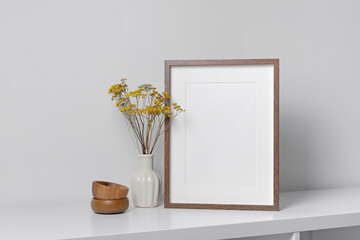 Wooden blank frame mockup for artwork, photo or print presentation. White minimalistic interior with dry flowers decor in vase