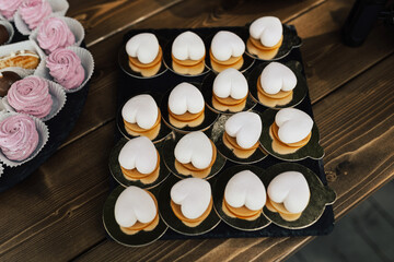 Many small heart-shaped cake on the wooden table, preparing for birthday party.
