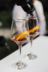 Two glasses of cocktails on the table in the bar. Bartender pours a sparkling wine in glass.