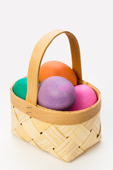A small wicker basket made of veneer with colored Easter eggs made of handmade soap.