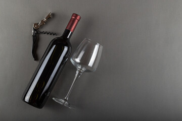 Corked red wine bottle, corkscrew and empty wine glass on gray background. Alcoholic drink....