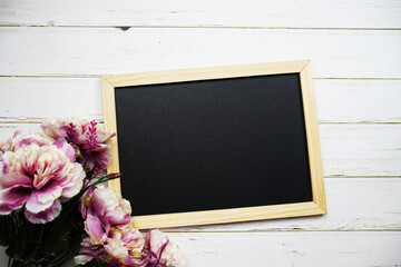 Empty chalk board with flower bouquet on wooden background