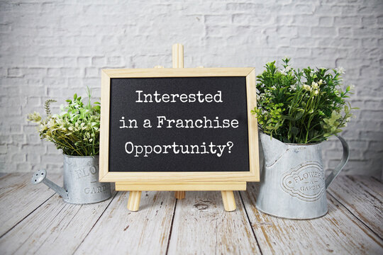 Interested in a franchise opportunity? text message write on blackboard with easel on wooden background