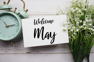 Welcome May text message with flower decoration on wooden background
