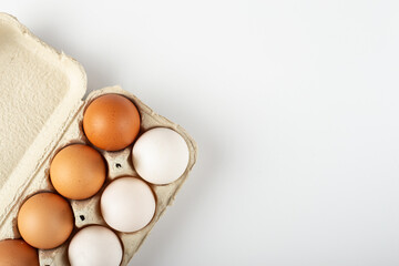 Raw chicken eggs in an egg tray on a white background.