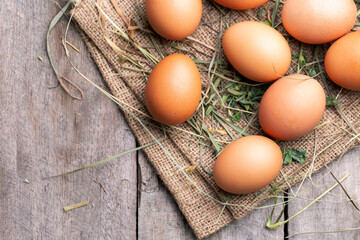 Brown chicken eggs lie on the background of hay and old boards.