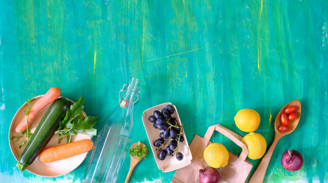 Fresh locally grown fruits and vegetables packed in eco-friendly paper bags, wooden dish and glass bottle, zero waste vegetarian nutrition concept