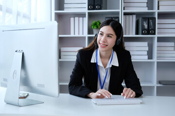 Asian confidence operator woman agent with headsets working in a call center at night Environment with her colleague team as customer service.they are smiling while working in office at night..