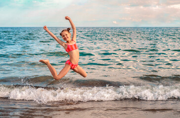 Jumping Child Girl Having fun Enjoying on Sea Beach. Happy Family Summer Holiday with Children.