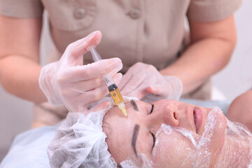 The cosmetologist makes injections of plasmolifting. Plasmolifting procedure. Blood in a test tube. Cosmetologist's hands.Close-up of the patient's face. The concept of cosmetology.