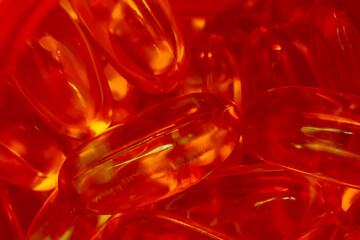 lots of yellow gelatin capsules on a red background. omega viramins, close-up, macro