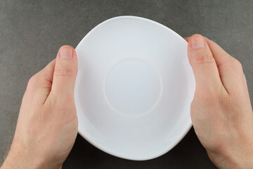 Hands hold empty white plate. Top view.