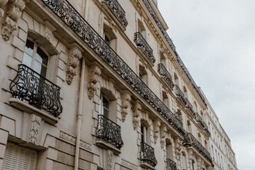 Exterior of aged residential building of beige color with glass windows and beautiful cast iron...