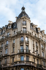 Fototapeta na wymiar Exterior of aged residential building of beige color with glass windows and beautiful cast iron balconies located in the center of Paris, France
