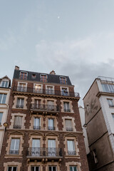 Fototapeta na wymiar Exterior of aged residential building of beige color with glass windows and beautiful cast iron balconies located in the center of Paris, France