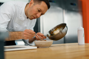 professional kitchen chef lays pieces of caramelized apple in freshly cooked oatmeal breakfast food concept