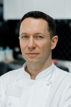 Professional Kitchen Serious Male Chef In White Coat Standing At Workplace Portrait