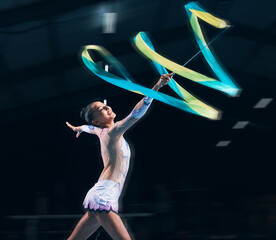 Ribbon gymnastics, woman and smile in motion blur of dancer, talent show and competition in dark arena. Happy female athlete, rhythmic movement and dancing for action, creative sports and performance