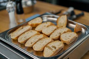 Professional kitchen fresh slices of bread with seasonings lie on a baking sheet close-up of the...