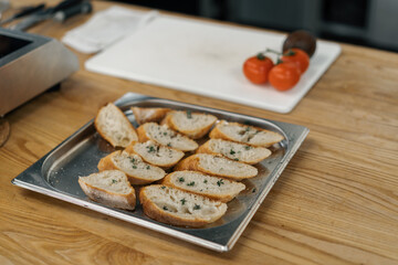 Professional kitchen fresh slices of bread with seasonings lie on a baking sheet close-up of the...