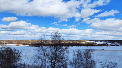 Beautiful landscape with sky, clouds and a river with ice on a sunny spring day
