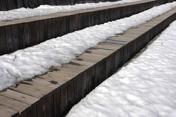 Melting on spring snow on the different surfaces of old brown wooden boards surface outdoors side view close up