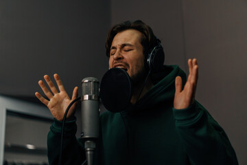 singer with headphones and microphone emotionally recording a new song in a professional recording studio
