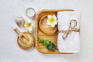 Spa and bathroom accessories on wooden tray, bath sea salt on wooden spoon, towel, sea stone, white orchids. Spa and massage products set conception. Top veiw