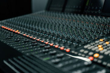 A recording studio control panel mixer with an equalizer faders buttons for broadcasting a recording of a song