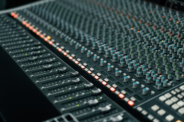 A recording studio control panel mixer with an equalizer faders buttons for broadcasting a recording of a song
