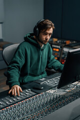 Sound engineer working in home music studio with monitors and equalizer on screen mixing and...