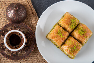 Traditional pistachio baklava with Turkish coffee on black background,top view
