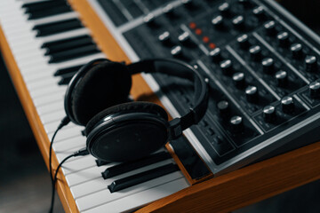 Fototapeta na wymiar headphones lie on an electronic keyboard piano Concept of a recording studio creating a song in the studio Recording