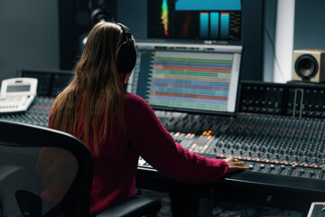 beautiful young sound engineer in bright clothes used digital audio mixer presses keys control panel