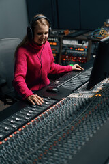 beautiful young sound engineer in bright clothes used digital audio mixer presses keys control panel