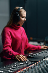 beautiful young sound engineer in bright clothes used digital audio mixer presses keys control panel