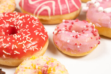 Donuts with red and pink glaze, side view. Lots of donuts, sweet and delicious food