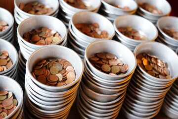 Several aluminum cups filled with Thai baht In Wat Pho Church, Bangkok, Thailand