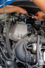 Close-up of a car mechanic changing oil in a mechanical workshop. Mechanic checking engine oil level in an auto car repair service center. A mechanics in uniform working in car repair and maintenance.