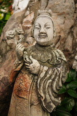 Fototapeta na wymiar Ancient sandstone sculptures dressed like Chinese people in various poses at Wat Pho, Bangkok, Thailand.