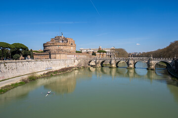 Fototapeta premium Rom, Italien, Apr. 2023 ein Ruderer auf dem Tiber mit der Ponte Sant Angelo und der Engelsburg im Hintergrund das Gebäude des Cassationsgerichts vor blauem Himmel